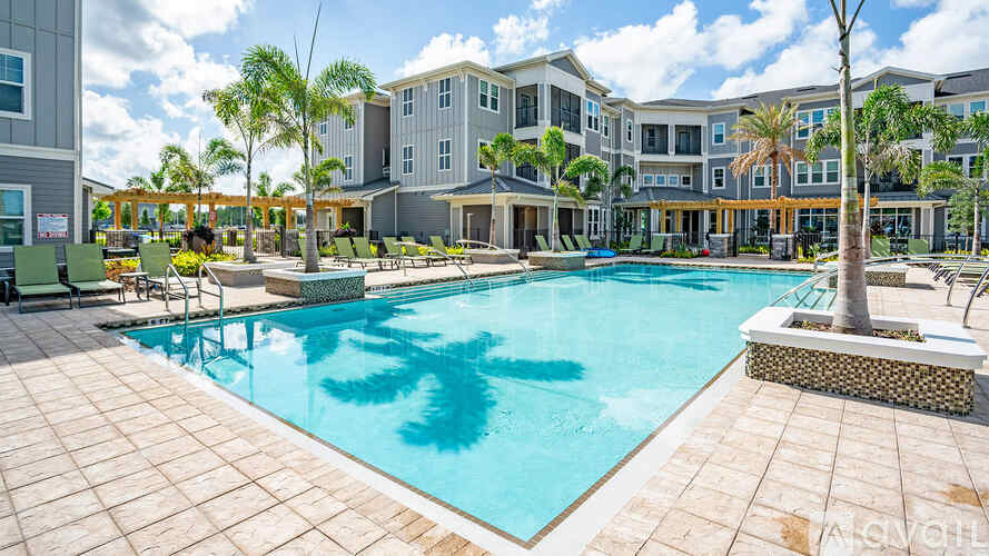 A large swimming pool surrounded by a tiled patio and lounge chairs.