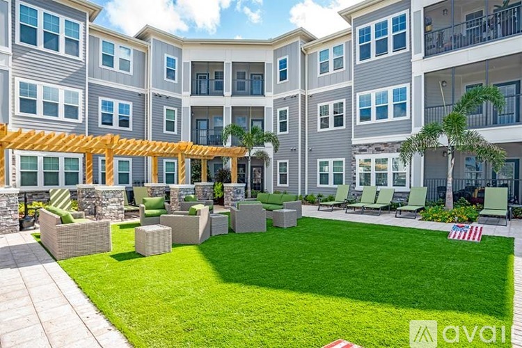 Apartment complex with a green lawn and a wooden pergola.