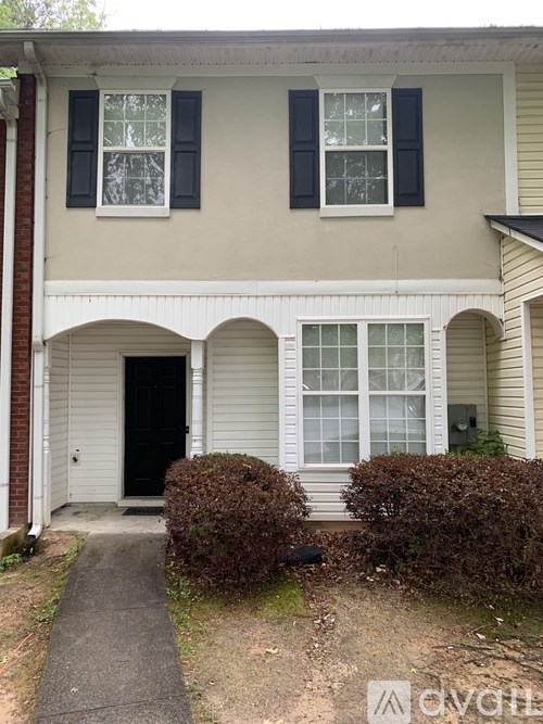 A beige house with black shutters and a black door.