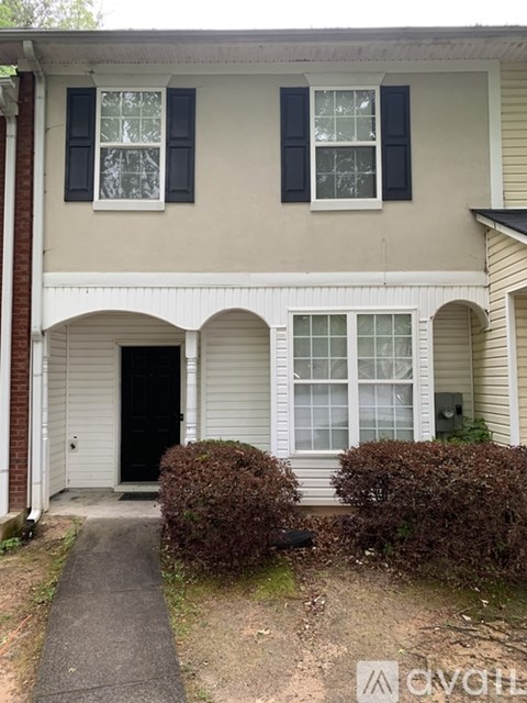 A beige house with black shutters and a black door.