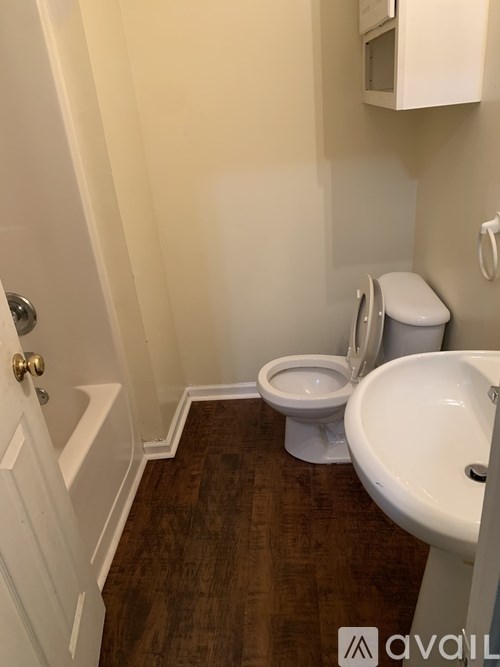 A white toilet sits next to a white sink in a small bathroom.