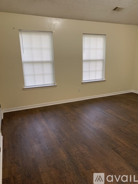 A room with wooden floors and two windows.