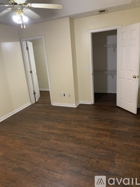 A room with a ceiling fan and wood flooring.