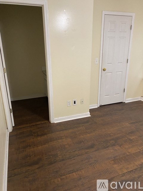 A room with a white door and wooden floors.