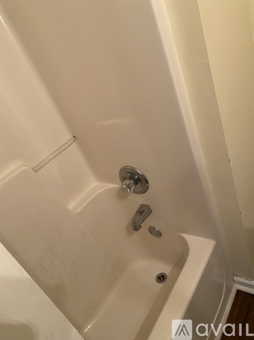 A white bathtub with a shower head and faucet.