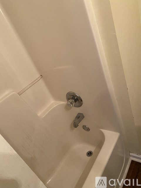 A white bathtub with a shower head and faucet.