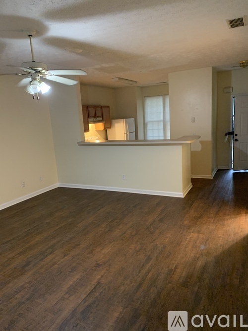 A room with a ceiling fan and wooden flooring.