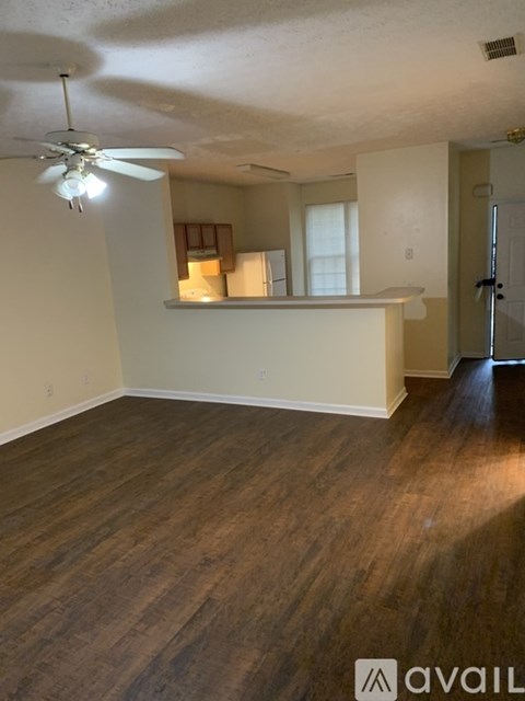 A room with a ceiling fan and wooden flooring.