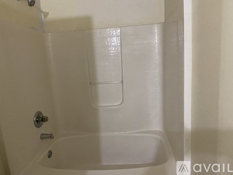 A white bathtub with a shower door and a shower head.