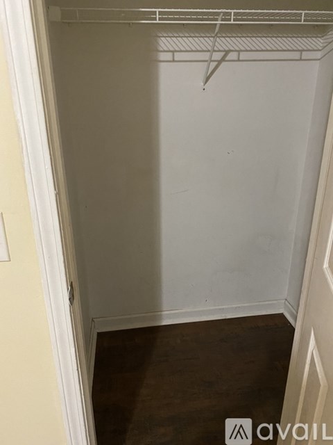 Empty white closet with a white door and a white wall.