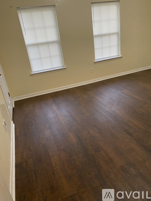A room with wooden floors and two windows.