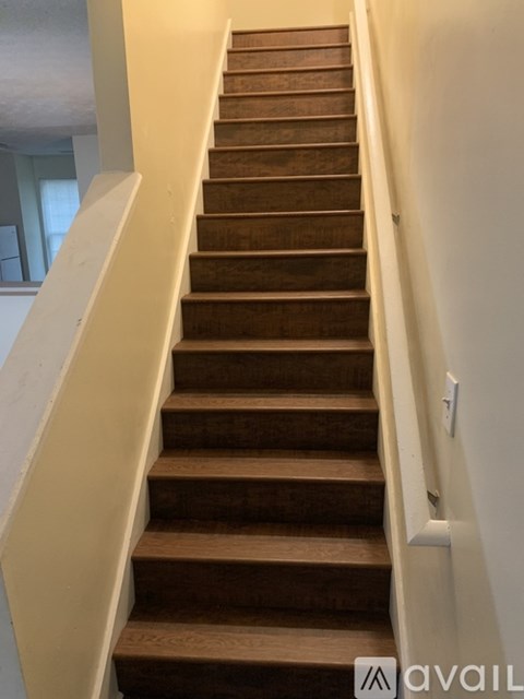 A long staircase with wooden steps and a white handrail.