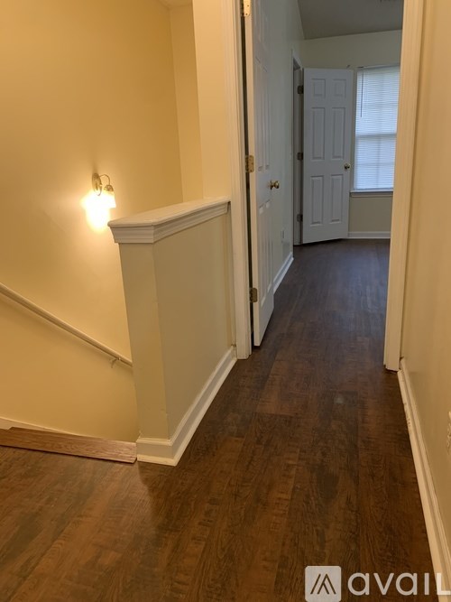 A hallway with wooden floors and white walls.