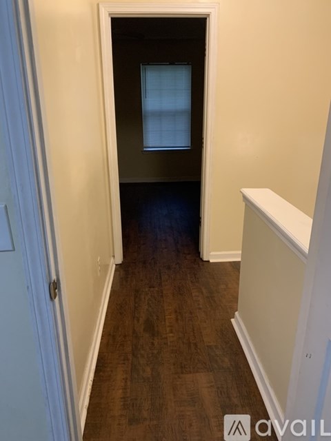 A hallway with a door on the left and a window on the right.