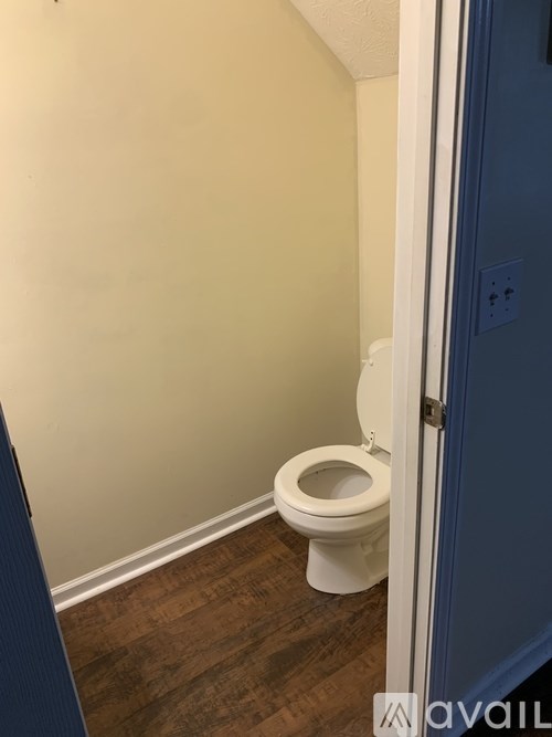 A white toilet in a small bathroom with a blue door.