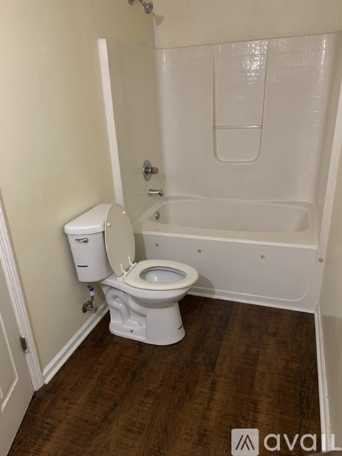 A white toilet with a white tank and a white bathtub in a bathroom.