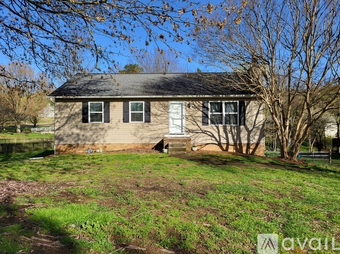 A house with a brown roof and a white door is surrounded by trees.