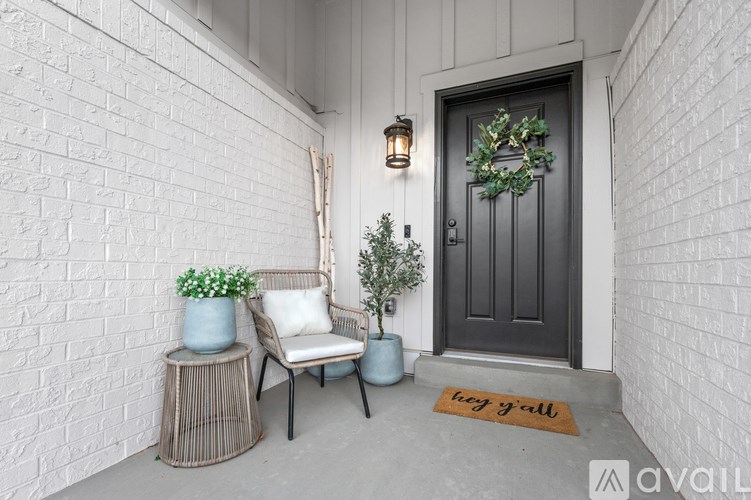 A front porch with a chair, a plant, and a door mat.