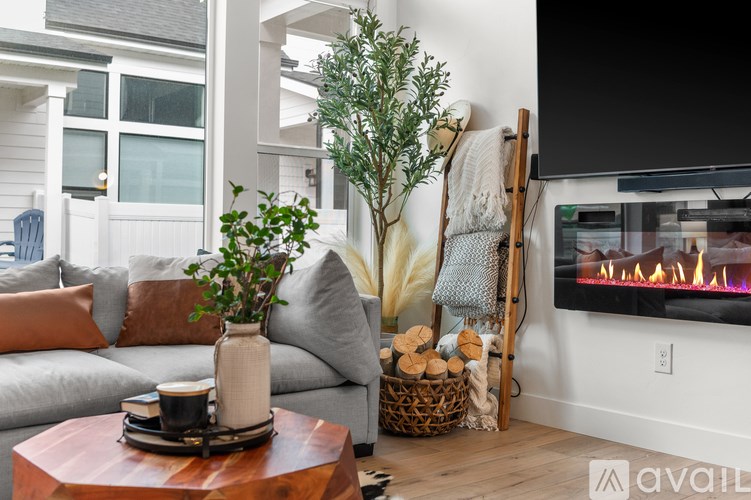 A living room with a grey couch, a wooden coffee table, a fireplace, and a TV mounted on the wall.