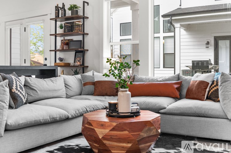 A modern living room with a grey sofa, a wooden coffee table, and a plant on it.