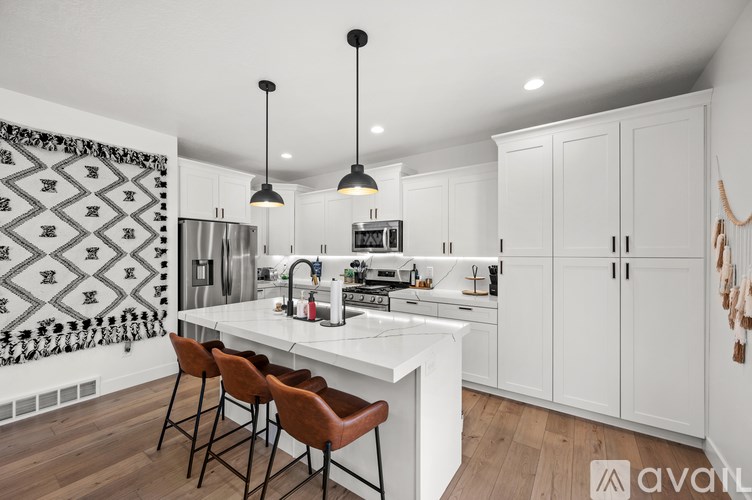 A kitchen with white cabinets and a white countertop with a black and white patterned wallpaper on the wall.