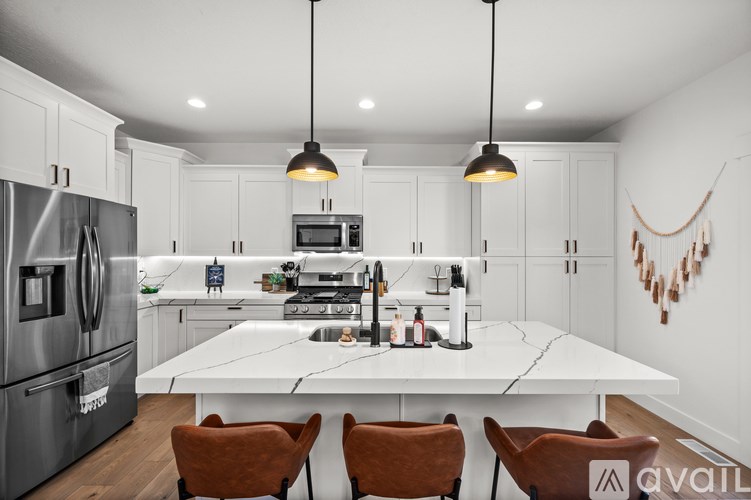 A modern kitchen with a white table and brown chairs.