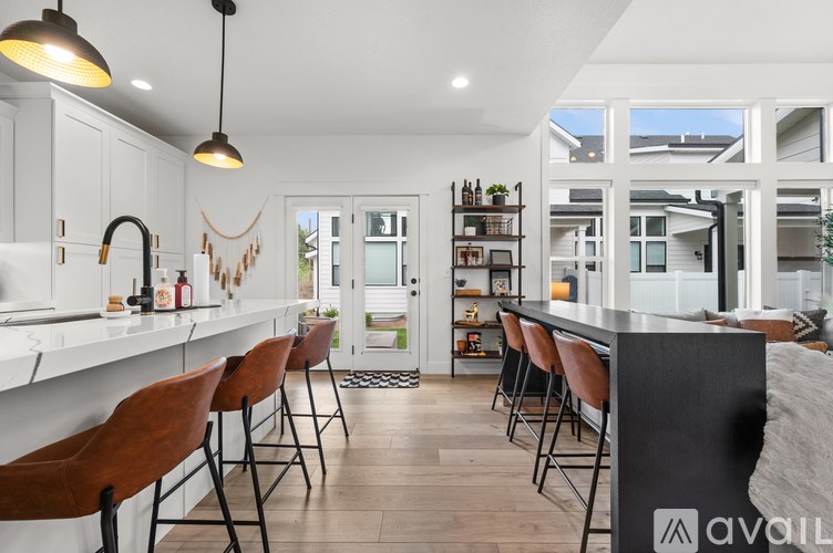 A modern kitchen with white cabinets and a bar area with brown chairs.