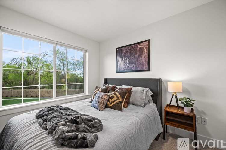 A bedroom with a large bed and a window overlooking a green area.