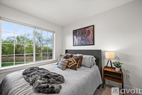 A bedroom with a large bed and a window overlooking a green area.