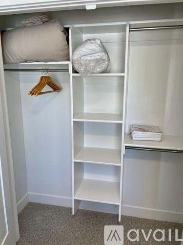 A white closet with a hanger and a bag on the shelf.