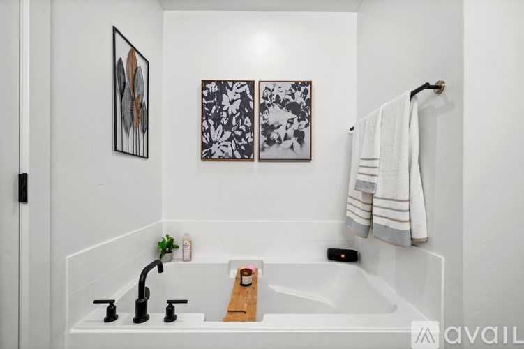 A bathroom with a white tub and a white towel hanging on the wall.