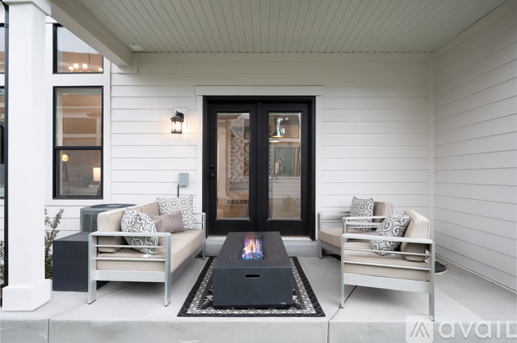 A modern outdoor seating area with a black coffee table and two white couches.