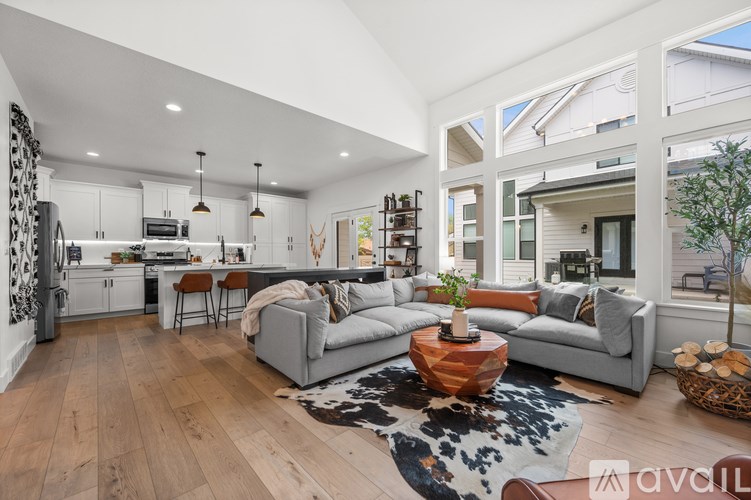 A modern living room with a grey sofa, wooden floors, and a black and white cowhide rug.
