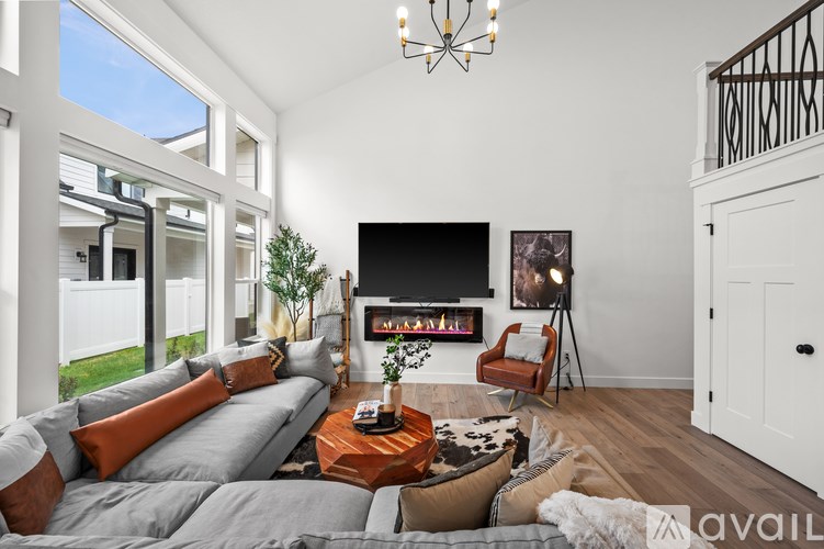 A living room with a grey couch, a coffee table, a fireplace, and a chandelier.