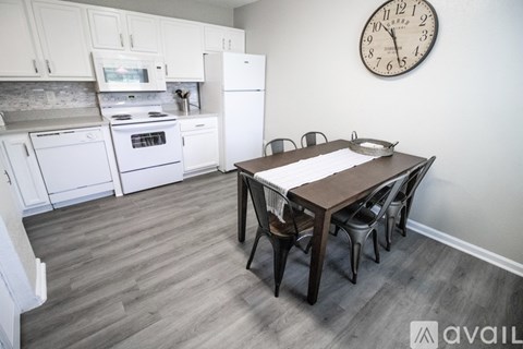 A kitchen with a table and chairs and a clock on the wall.