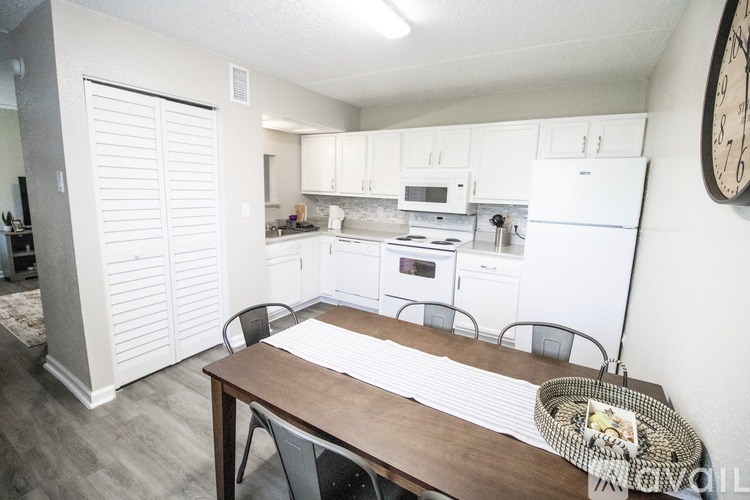 A kitchen with white appliances and a wooden table.