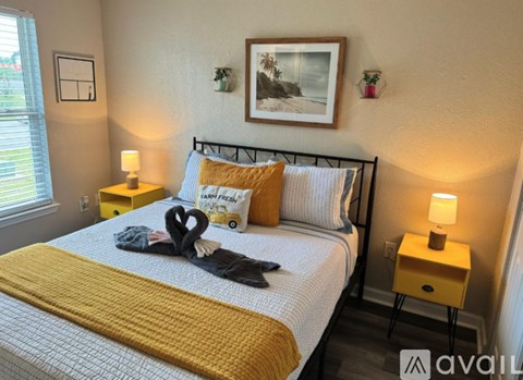A bedroom with a bed, two lamps, and a picture on the wall.