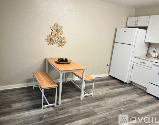 A kitchen with a table and chairs in the foreground and a refrigerator in the background.