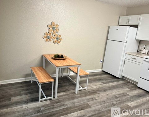 A kitchen with a table and chairs in the foreground and a refrigerator in the background.