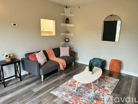 A living room with a grey couch, a white coffee table, and a rug with a floral pattern.