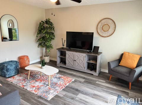A living room with a television, a plant, and a chair.