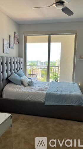 A bedroom with a bed, pillows, and a ceiling fan.