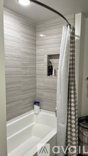 A white bathtub with a shower curtain and a mirror above it.