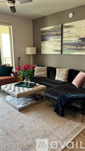 A living room with a black couch, a coffee table, and a painting on the wall.