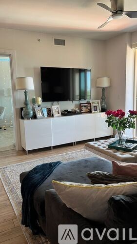 A living room with a grey couch and a white cabinet with a flat screen TV on top.