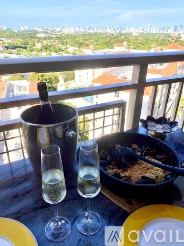 A bottle of champagne is on a table with two glasses of champagne and a pan of food.