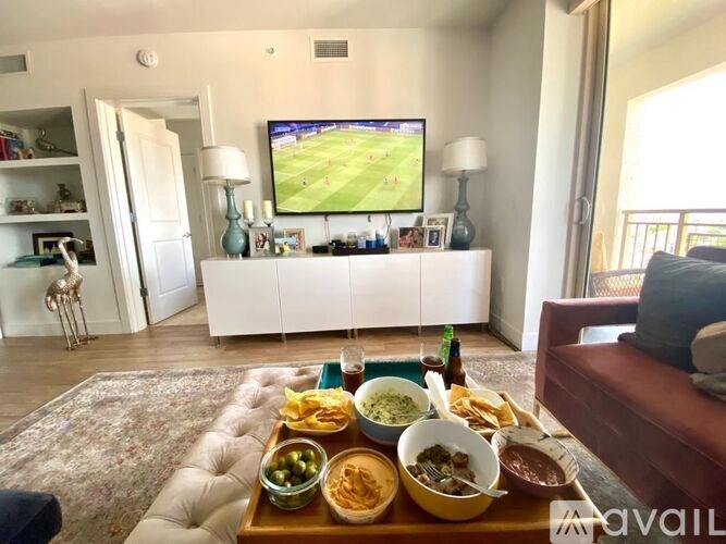 A living room with a flat screen TV and a tray of food on the coffee table.