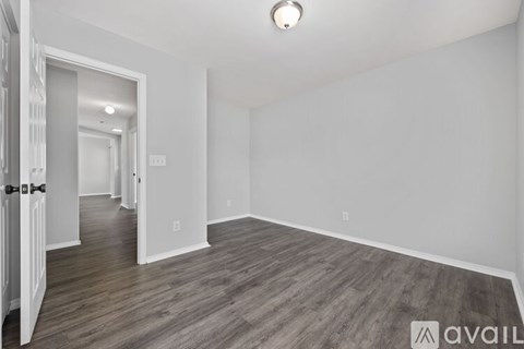 A spacious room with wooden flooring and white walls.