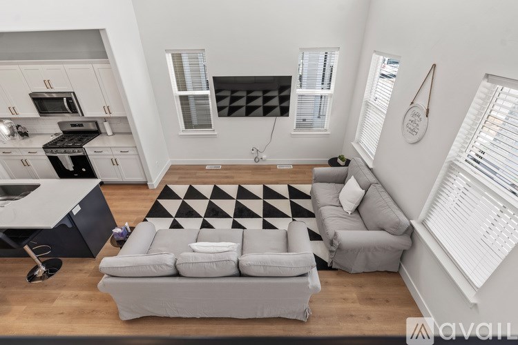 A modern living room with a grey sofa and a black and white checkered rug.