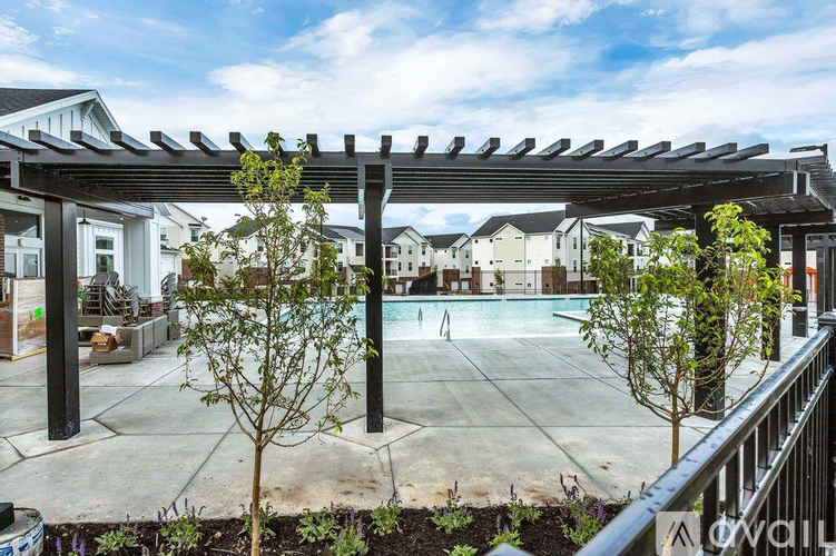 A patio with a pergola and a pool in the background.